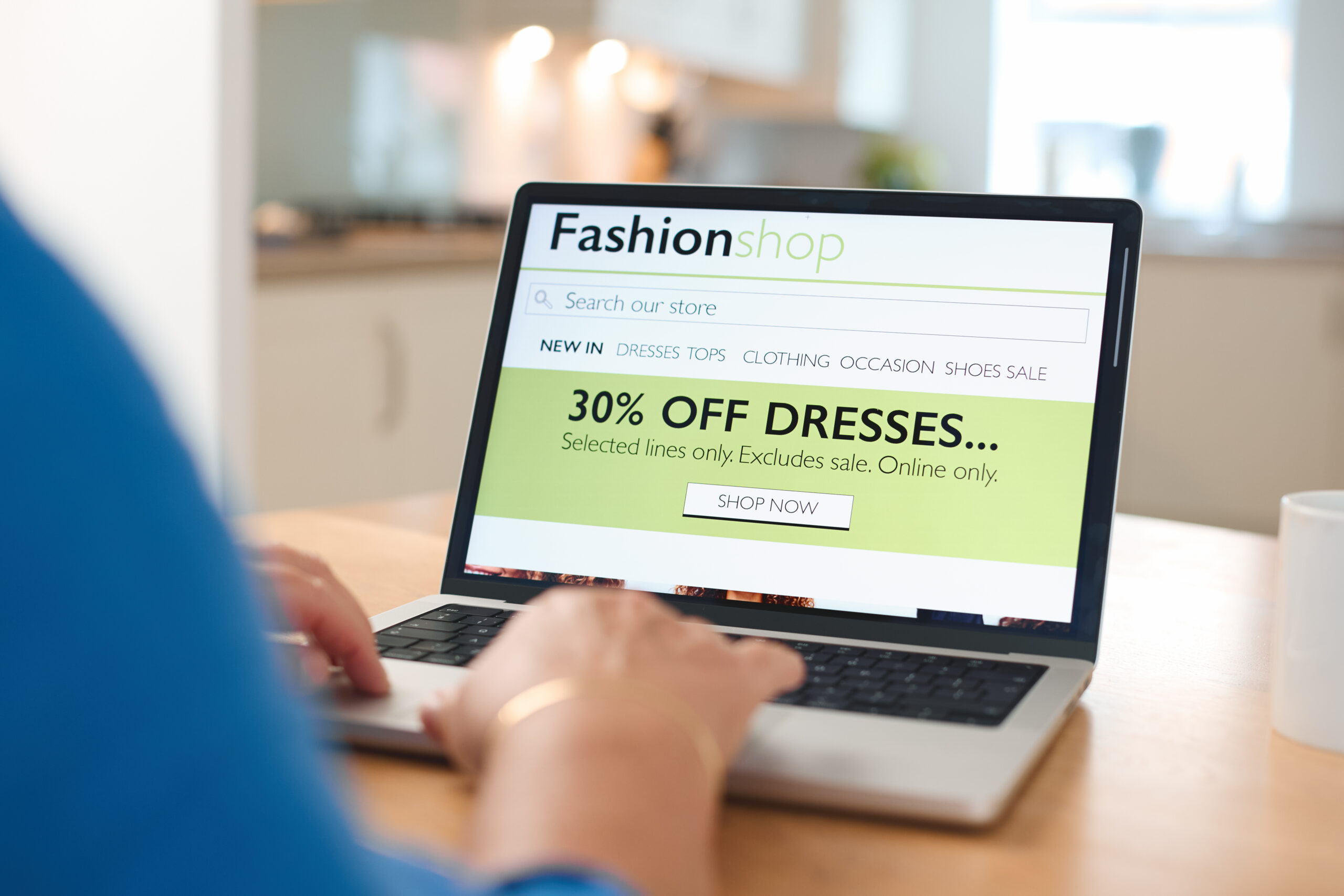 online shopping experience in a cozy kitchen with a laptop displaying discounts on dresses